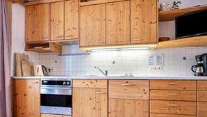 A kitchen with wooden cabinets, a stainless steel oven, a sink, and a coffee maker.
