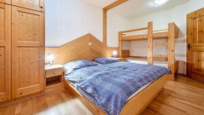 A wooden bunk bed room with a desk and wardrobe.
