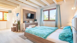 A modern bedroom with a wooden ceiling, a bed with patterned bedding, a TV on the wall, and a window with curtains. - Holiday Home 'Villa Sun Club Home' with Private Pool, Wi-Fi and Air Conditioning (Llucmajor)