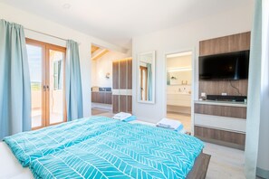 A bedroom with a bed, a TV, and a bathroom visible in the background.