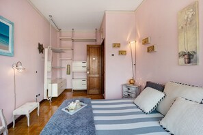 A bedroom with a bed, bedside tables, a wardrobe, a bench, and a door leading to another room.