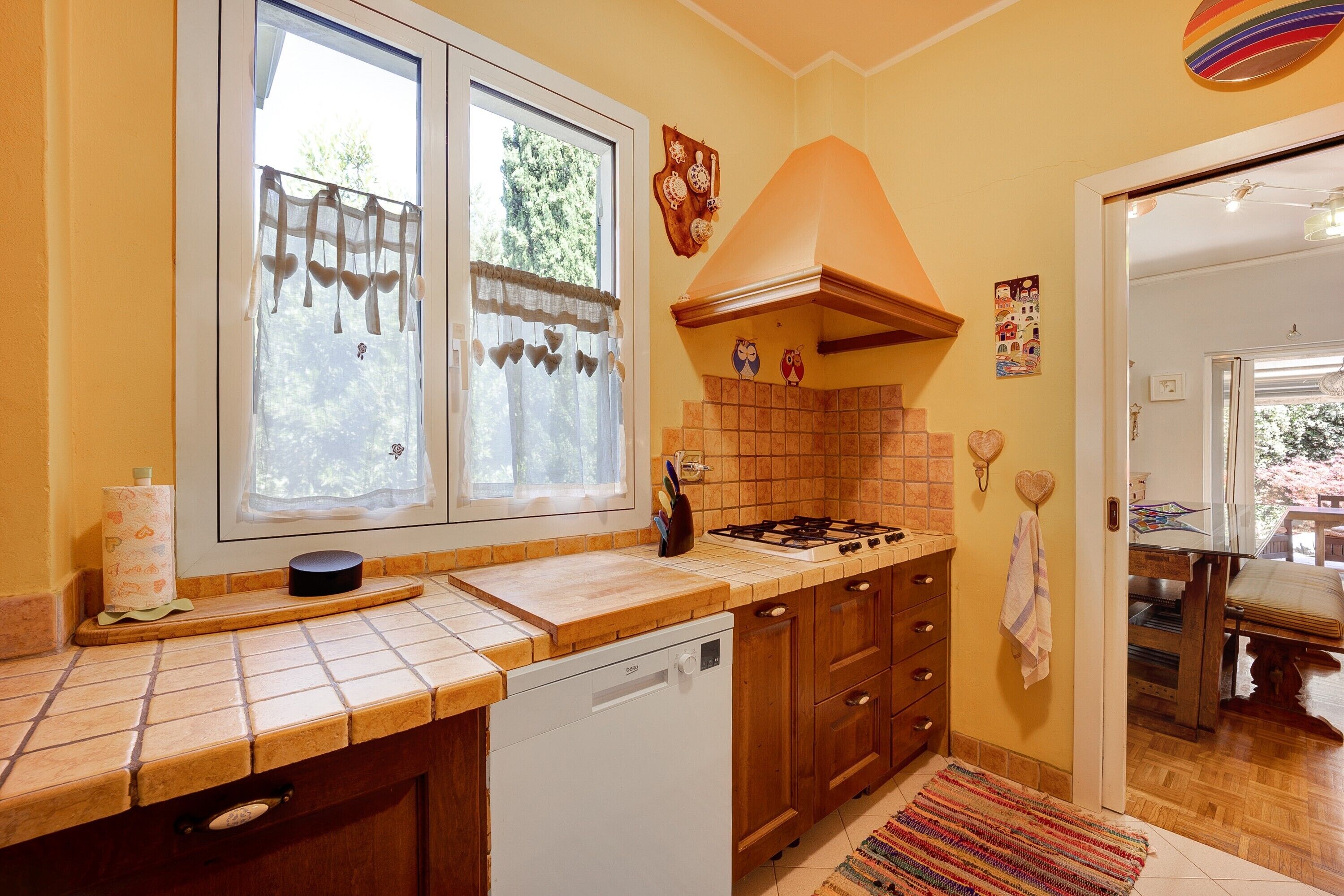Une cuisine équipée d’un lave-vaisselle, d’une cuisinière et de meubles de rangement en bois.