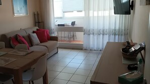 Un salon comprenant un canapé, une table à manger, des chaises et un téléviseur.