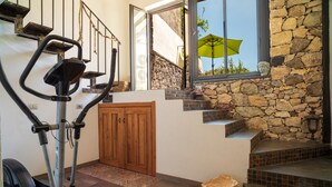 A staircase with stone walls, a wooden door, and exercise equipment. - Holiday Home "Sikelia Relais" with Mountain View & Wi-Fi (Linguaglossa)