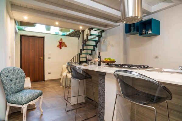 Een moderne keuken met een marmeren aanrechtblad, een ingebouwde kookplaat en een houten deur.