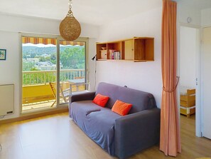 Uma sala de estar com sofá, luminária pendente, estante de livros e vista por uma porta deslizante.