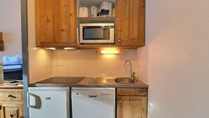 Una cocina compacta con armarios de madera, microondas, fregadero y lavavajillas.