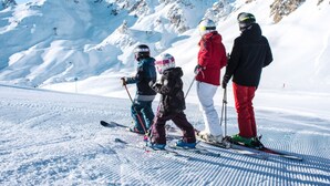 Un groupe de skieurs sur une pente enneigée, avec des montagnes en arrière-plan.