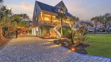 Ein zweigeschossiges Haus mit einer markanten Treppe, einem gepflasterten Weg und umliegender Bepflanzung.