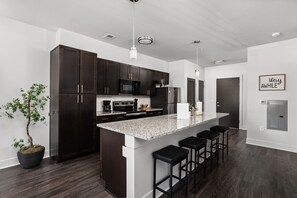 A modern kitchen with dark cabinets, a granite countertop, and a bar stool area.