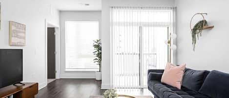 A modern living room with a dark sofa, a round coffee table, and a television on a wooden stand.