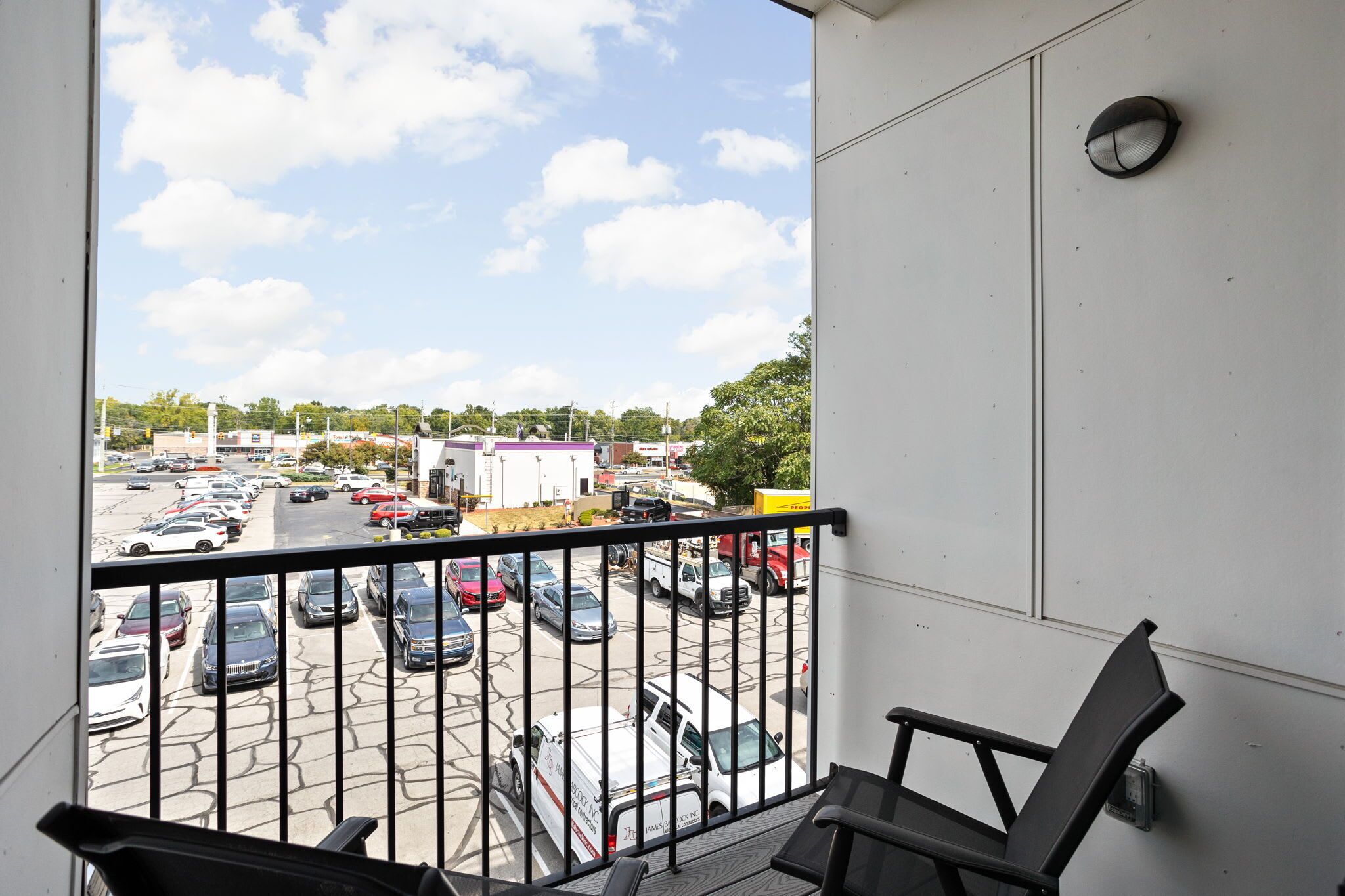 A balcony with a view of a parking lot and buildings in the distance.