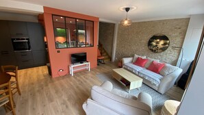 Een moderne woonkamer met een televisie, bank en een eethoek.