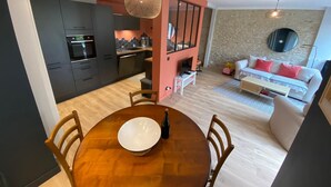 Een moderne keuken met donkere kastjes, een eettafel met stoelen, en een zithoek met een bank en salontafel.