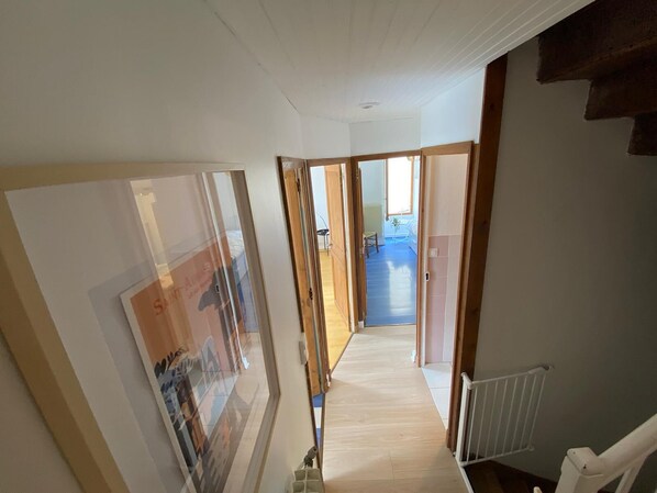 A hallway with wooden doors leading to a room with a blue floor. - Maison en Pierre 4 Chambres, Mer, Commerces 150 Metres (Saint-Aubin-sur-Mer)