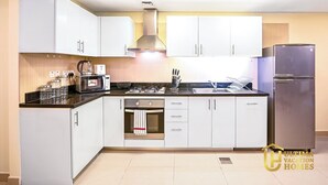 Una cocina moderna con gabinetes blancos, un refrigerador de acero inoxidable, un horno empotrado y un microondas.