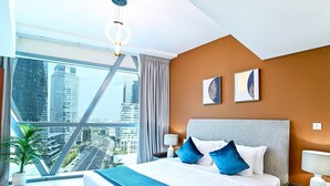 Una habitación de hotel moderna con una cama grande, vistas a la ciudad y obras de arte en la pared.