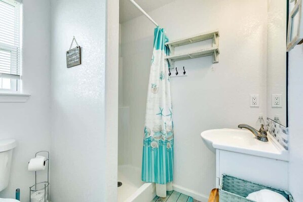 A bathroom with a bathtub, a sink, and a shower curtain.