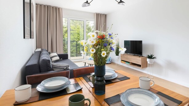 A modern living room with a sofa, dining table, and TV.