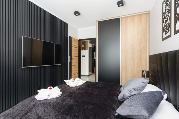 Ein modernes Schlafzimmer mit einem großen Bett, einem Flachbildfernseher und einem Holzschrank.