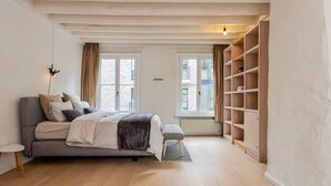 A bedroom with a bed, bedside tables, a window, and built-in shelving. - Spacious house for 6 – central Antwerp (Antwerpen)