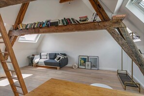 Une pièce de style loft avec une échelle en bois, un canapé et une bibliothèque remplie de livres.