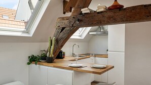 A modern kitchen with a wooden beam ceiling, skylight, and white cabinetry. - Contemporary 1-BR Duplex in Antwerp (Antwerpen)