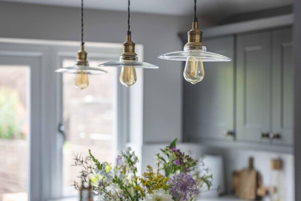 A kitchen with pendant lights, a window, and a vase of flowers.