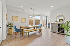 A dining area with a wooden table and chairs, a bench, and a buffet cabinet. - Pacific Beach Paradise by Cardo | Spacious Retreat (San Diego)