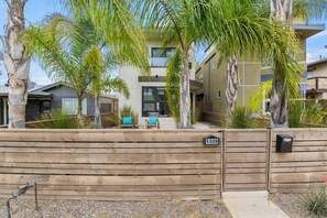 A modern building with a wooden fence, palm trees, and a sign with the number 1328.