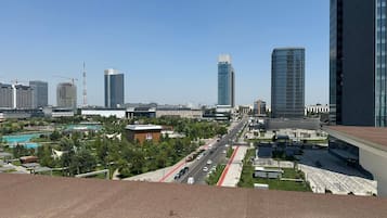 A cityscape with modern buildings, a clear road, and a green park area.