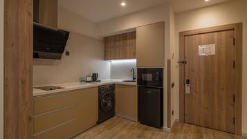 A compact kitchen with wooden cabinets, a built-in washing machine, a microwave, and a sink.