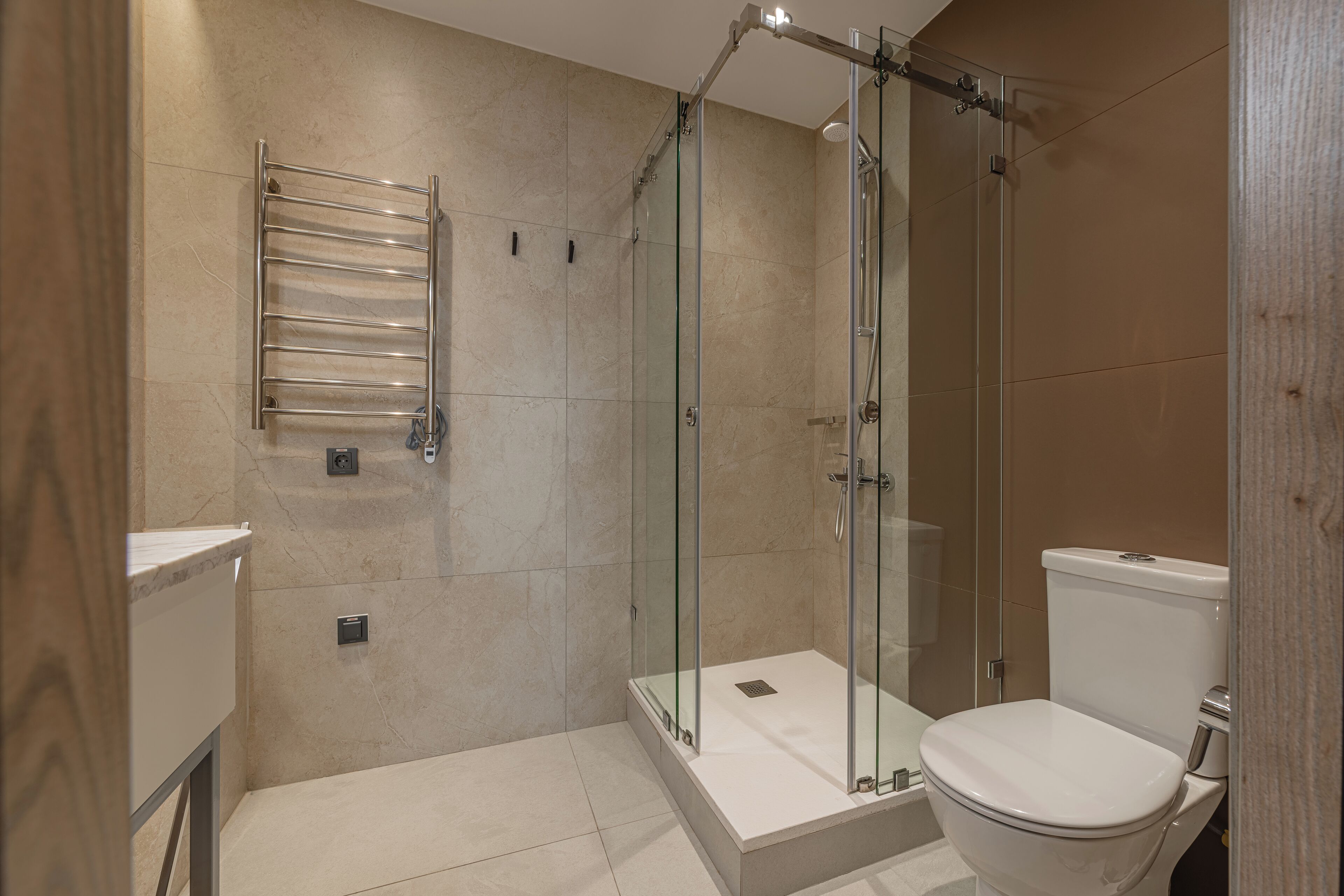 A modern bathroom with a glass-enclosed shower, a white toilet, and a towel rack.