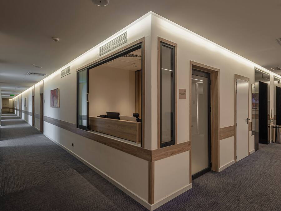 A hotel corridor with a reception desk, a trash can, and a door with a sign.