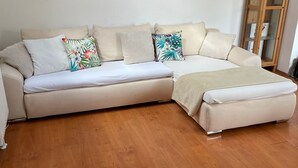 Un salon moderne avec un canapé d’angle, une vitrine et un plancher en bois.