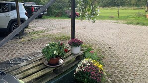 Un espace extérieur abrité, doté d’un banc en bois, de plantes en pot et d’un chemin pavé.