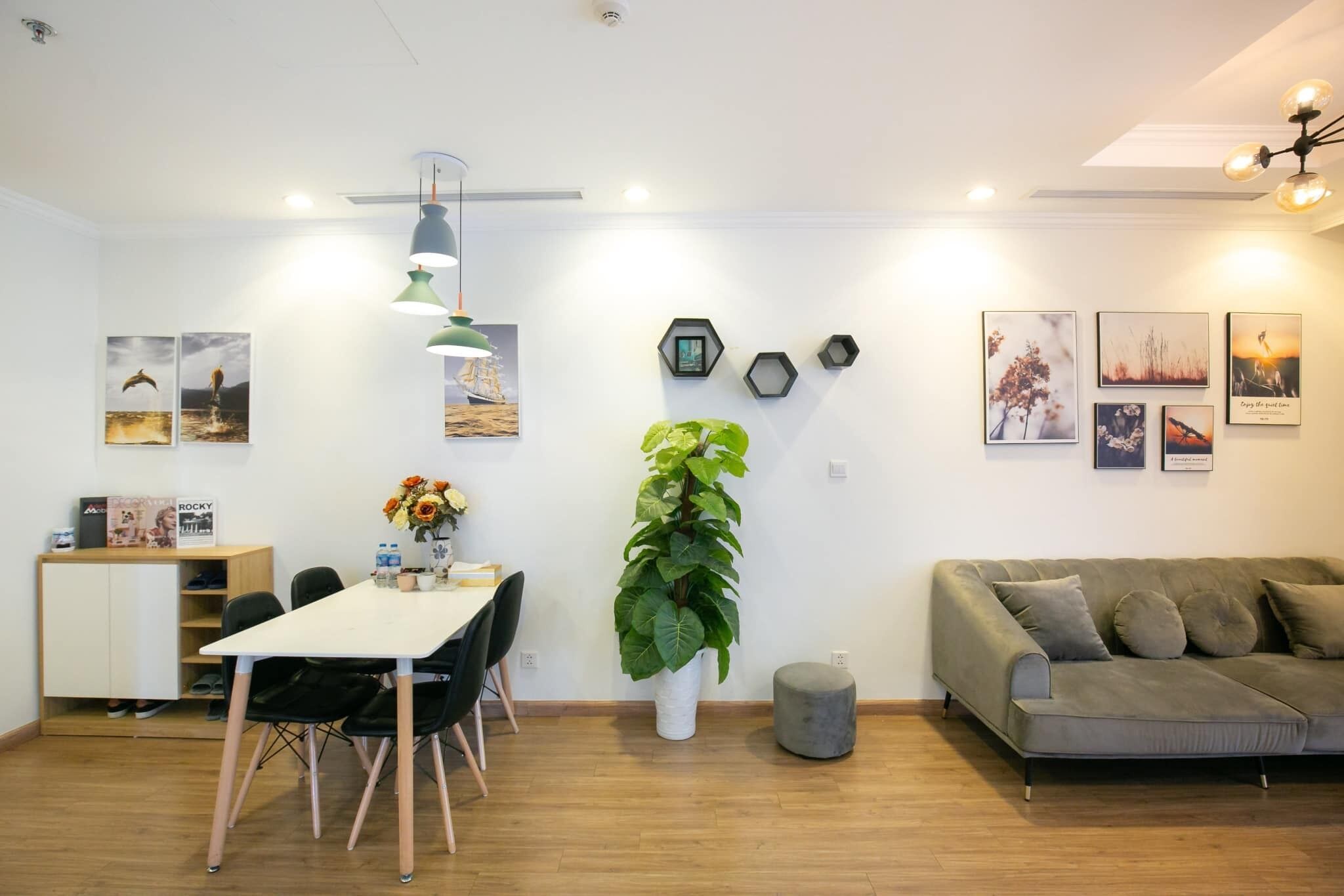 Una sala de estar moderna con un sofá, una mesa de comedor con sillas y una planta grande en maceta.