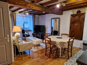 Un salón acogedor con techo de madera, televisor, mesa de comedor con sillas y un aparador.