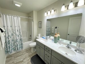 A bathroom with a shower, toilet, two sinks, a mirror, and a towel rack. - The Great Escape Chalet @ Spring Brook Resort (Wisconsin Dells)