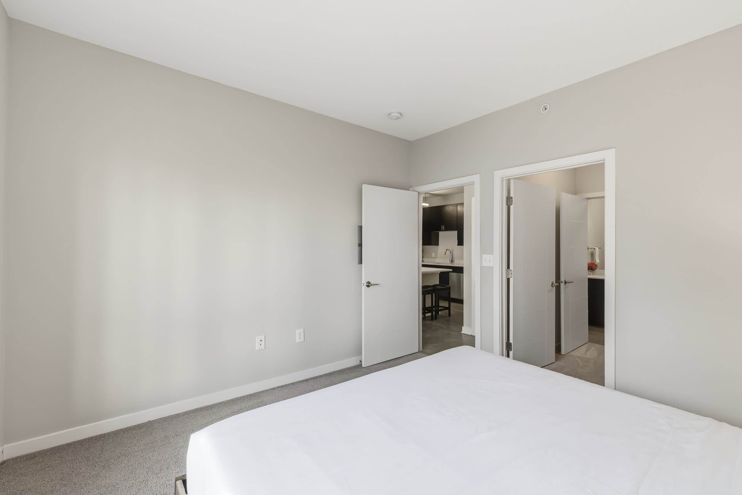Une chambre à coucher avec un grand lit, une armoire et une porte donnant sur une salle de bain.