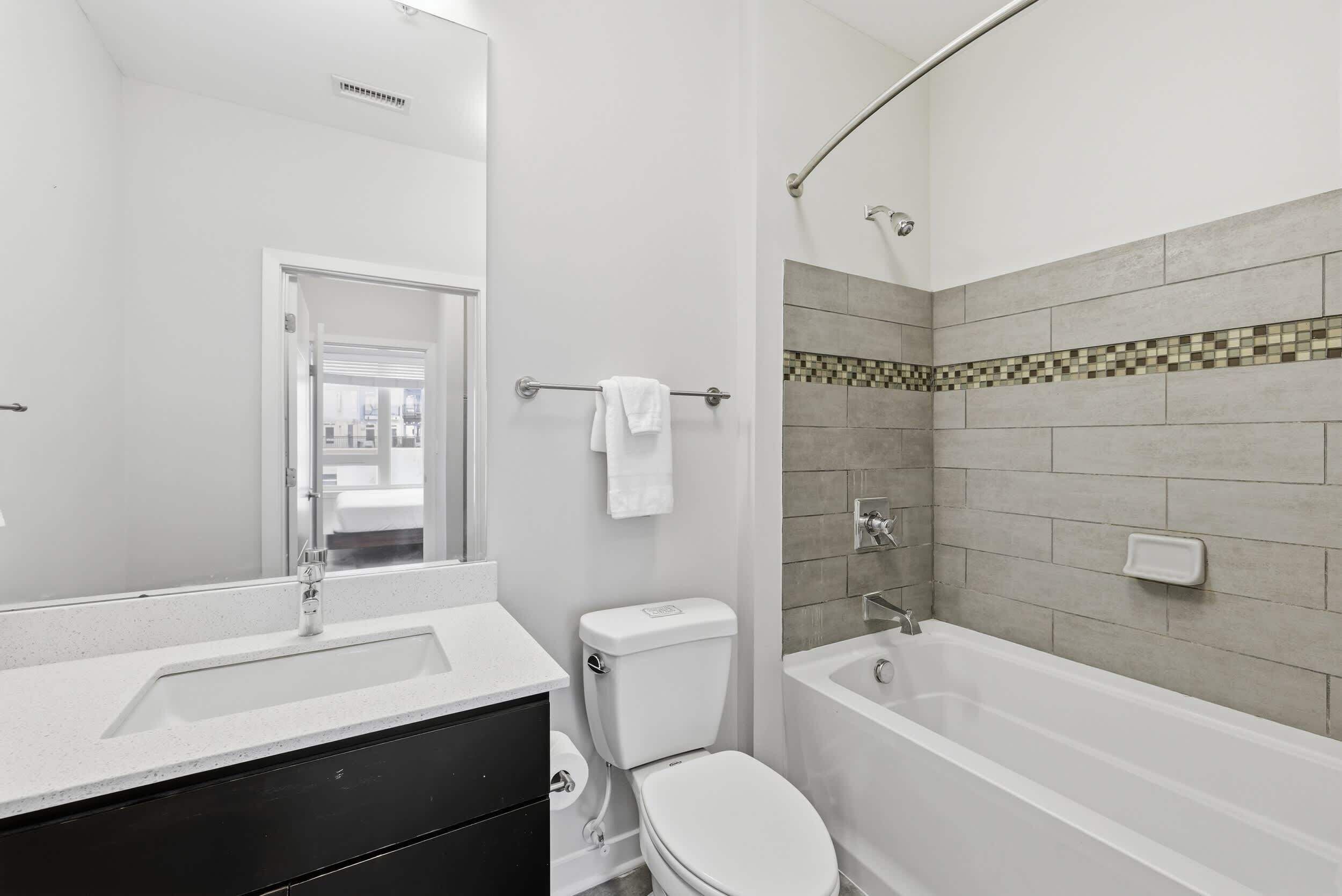 A modern bathroom with a white sink, toilet, and bathtub.
