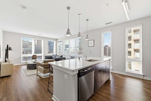 Un apartamento moderno con isla de cocina, comedor y sala de estar con sofá y mesa de centro.
