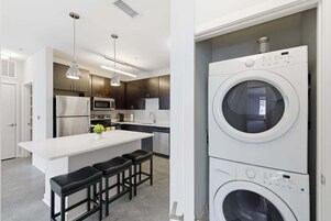 Una cocina moderna con una isla central, electrodomésticos de acero inoxidable y lavadora y secadora integradas.
