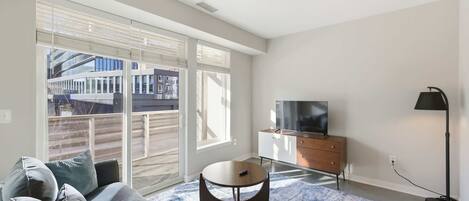 A modern living room with a sofa, a coffee table, a TV, and a floor lamp.