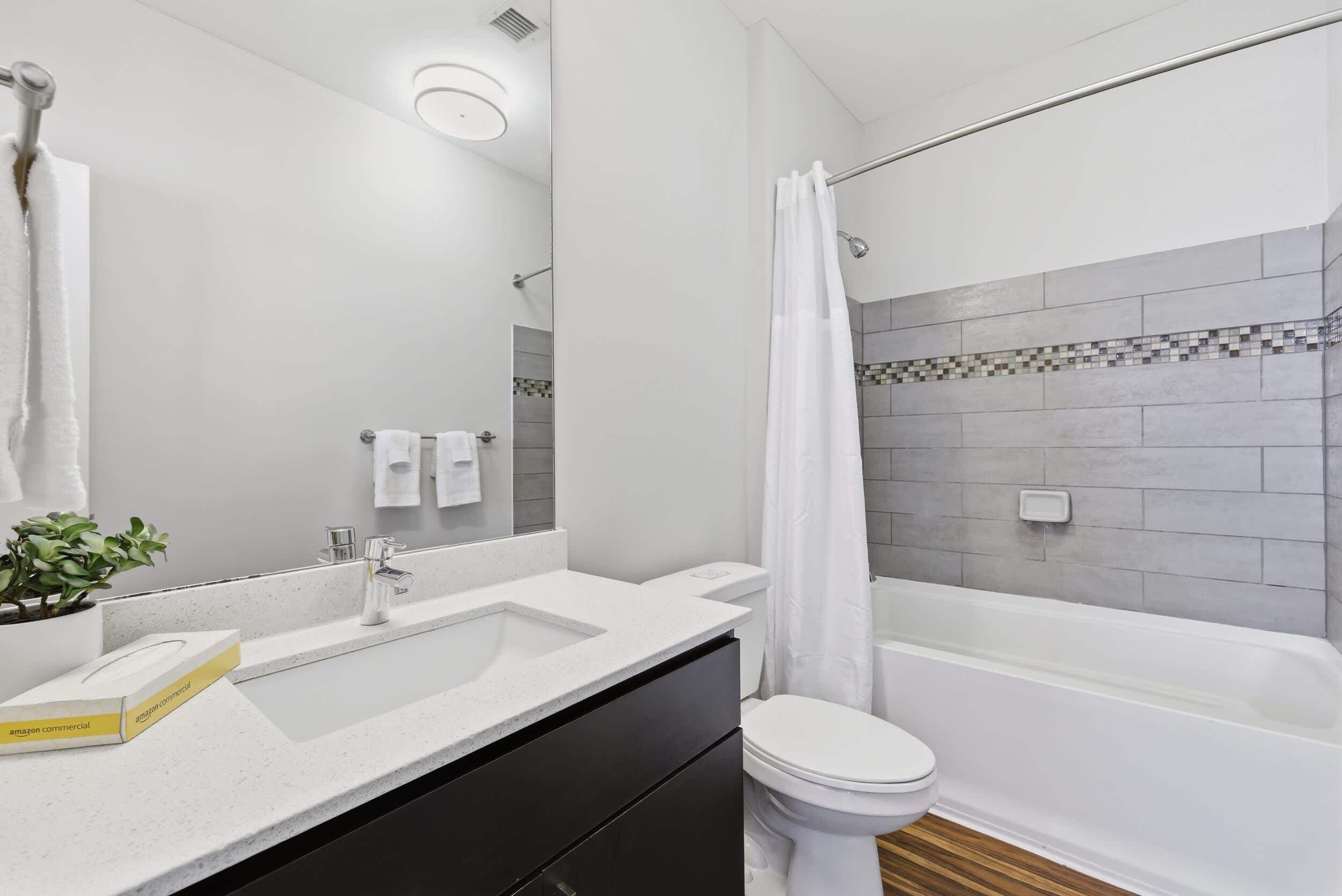Egy modern fürőszoba, fehér mosdókagylóval, WC-vel és fürdőkáddal.