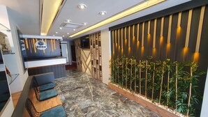 A reception area with a marble floor, a reception desk, a wall-mounted clock, and a vertical bamboo plant display.