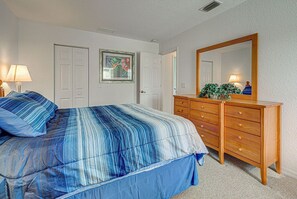 A bedroom with a bed, a dresser, a mirror, and a door. - Victoria | Pool | Bikes (Port Charlotte)