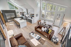 A spacious open-plan living area with a kitchen, dining space, and a large window providing a view of the outdoors.