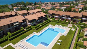 A resort with a large swimming pool, multiple villas, and a view of the sea and mountains. - Holiday apartment near the center with swimming pool, air conditioning, parking lot (Lazise)