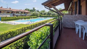 A poolside area with a view of a swimming pool, lounge chairs, and a table. - Holiday apartment near the center with swimming pool, air conditioning, parking lot (Lazise)